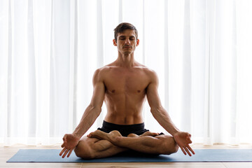 Young strong man doing yoga meditation breathing routine in the morning - obrazy, fototapety, plakaty