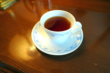 木目調のテーブルに置かれた白いティーカップと紅茶
