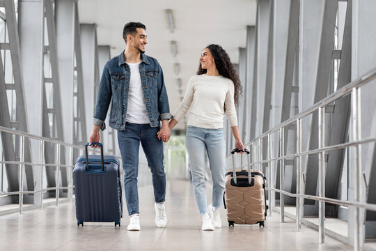 Happy Travellers. Portrait Of Young Arab Couple Walking With Suitcases At Airport
