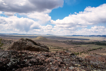 blue sky with white clouds over a valley with hills and mountains