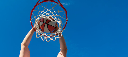 top view of basketball player throws the ball into the hoop outdoor, motivation. Horizontal poster design. Web banner header, copy space. © Olena
