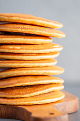 Pancakes for breakfast. Cover with pancakes. A stack of pancakes on a wooden board with honey. Honey pours on pancakes. Dessert. Favorite breakfast. Beautiful food cover.American breakfast. 