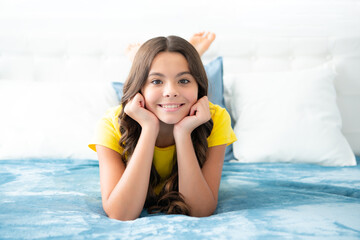 Teenager child girl resting in bed at home bedroom. Kid relaxing in bedroom interior. Kid daydreaming, dreaming.