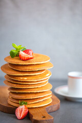 Pancakes for breakfast. Cover with pancakes. A stack of pancakes on a wooden board with honey. Honey pours on pancakes. Dessert. Favorite breakfast. Beautiful food cover.American breakfast. 
