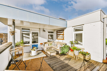 Relaxation area with a sofa, table and chairs, plants on a spacious balcony of a multi-storey...
