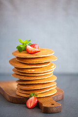 Pancakes for breakfast. Cover with pancakes. A stack of pancakes on a wooden board with honey. Honey pours on pancakes. Dessert. Favorite breakfast. Beautiful food cover.American breakfast. 