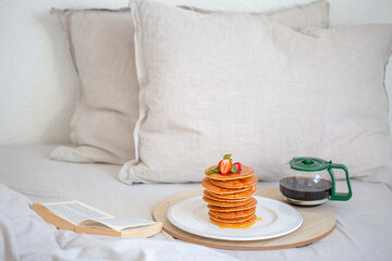 Bed with book and breakfast. Coffee and pancakes in bed. Have breakfast in bed. Hotel. Breakfast. Pancakes with coffee. Beautiful breakfast in bed 