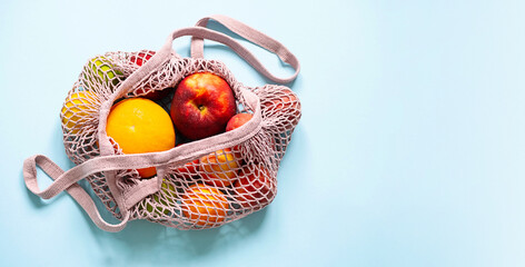 String mesh bag for grocery with various fruits. Reusable shopping tote bag, zero waste concept.