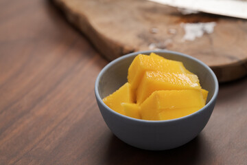 Fresh sliced mango in a ceramic bowl on walnut table