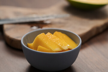 Fresh sliced mango in a ceramic bowl on walnut table