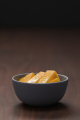 Fresh sliced mango in a ceramic bowl on walnut table