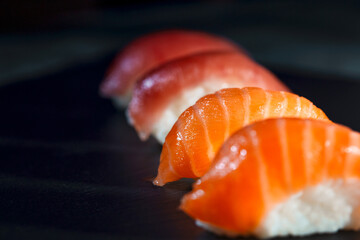 Delicious sushi with salmon and tuna. Pieces of food on black board, selective focus. Japanese...