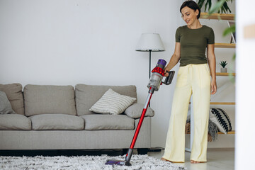 Woman vacuuming floor with rechargeable vacuum cleaner