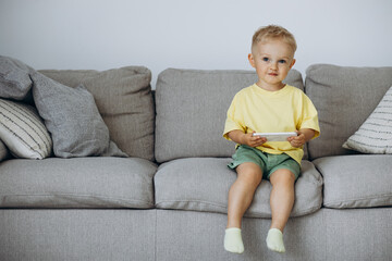 Little boy sitting on sofa and using phone