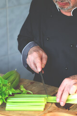 The hands of the cook cut the stalks of celery. Fresh celery.