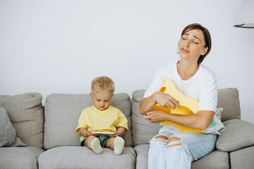 Woman with her son sitting on sofa and asking to pee in pot