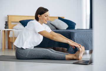 Young woman practicing yoga at home on mat