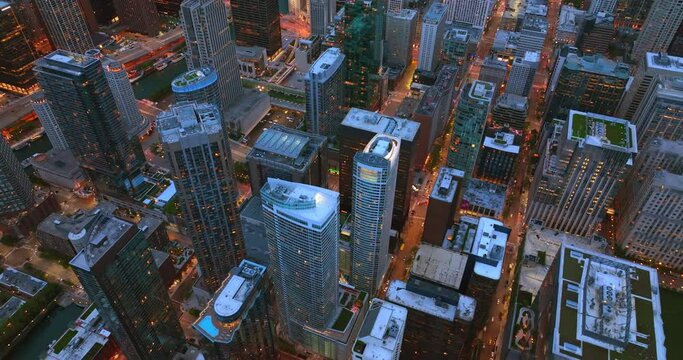 Flying over the tops of amazing skyscrapers. Well-lit streets of Chicago city, Illinois, USA at evening time.