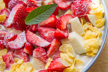 Cornflakes with oat milk and fruit - apple, pear and strawberries decorated with mint leaf