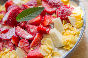 Cornflakes with oat milk and fruit - apple, pear and strawberries decorated with mint leaf