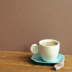 Cup of coffee on wooden table. brown wall background