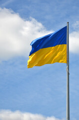The national flag symbol of Ukraine waving against the blue sky with white clouds. Independence and patriotism concept. Free copy space