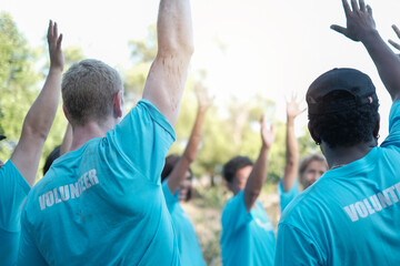 Naklejka premium Volunteering. Team of volunteers in uniform outdoors planting trees digging ground talking cheerful.