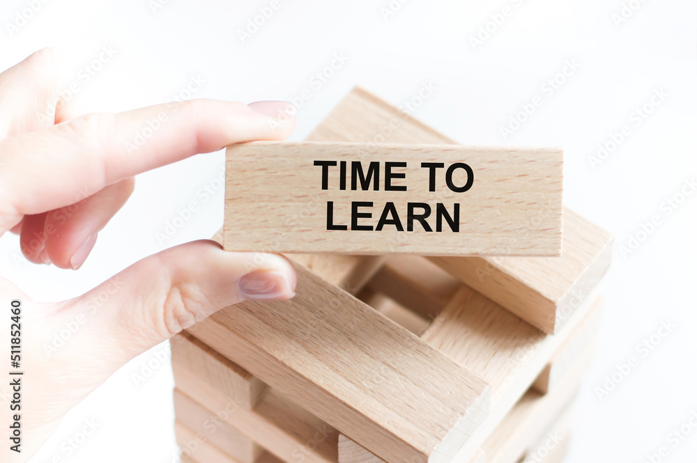 Aufkleber time to learn text on a wooden bar in a person's hand on a light background