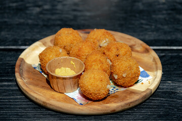 Bitterballen, Dutch meat-based snack in white plate served with mustard on wooden tabel background, Typically containing a mixture of beef or veal, Bitterballen are one of Holland's favorite snacks.