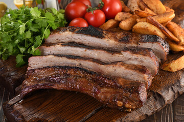 Delicious Baked Grilled Sliced pork belly with barbeque sauce plating on wooden plate,  herbs and vegetables and potatoes