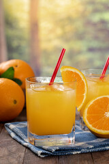 Glass of orange juice with rural summer background