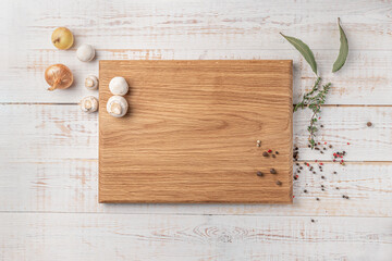 square wooden cutting board with mushrooms and spices on a white background. mockup with copy space for text, top view