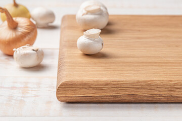 Fototapeta na wymiar square wooden cutting board with mushrooms and spices on a white background. mockup with copy space for text, side view, close-up