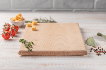 Fototapeta na wymiar square wooden cutting board with cherry tomatoes, cheese and spices on a white background. mockup with copy space for text, side view