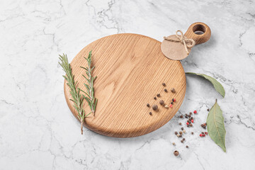 round wooden cutting board with a handle. thyme and spices on a white marble background. mockup...