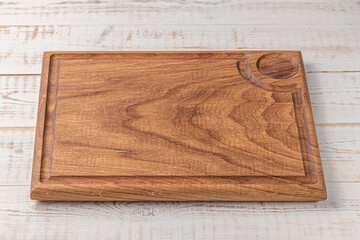 rectangular cutting board with edging and place for a bowl of sauce on a white wooden table. mockup of a food background with copy space, side view