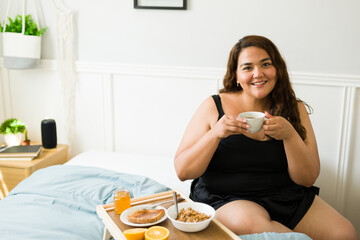 Beautiful big woman enjoying breakfast in bed