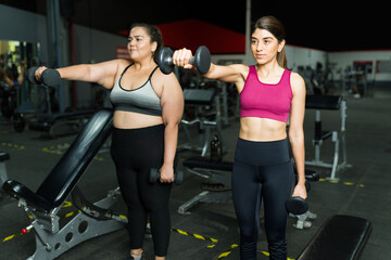 Fototapeta na wymiar Latin trainer and obese woman using weights
