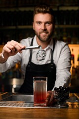 beautiful close-up on ice cube over glass with cocktail on bar counter