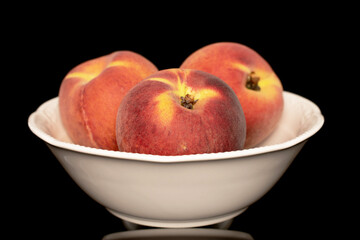 Three sweet organic peaches on a white ceramic plate, close-up, isolated on a white background.