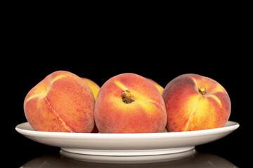 Several sweet organic peaches on a white ceramic plate, close-up, isolated on a white background.