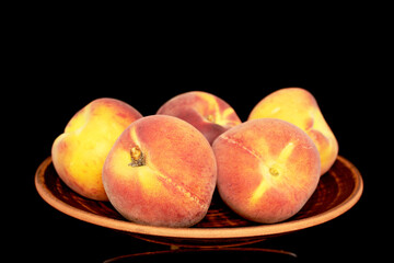 Several sweet organic peaches on a  ceramic plate, close-up, isolated on a black background.