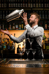 tower made of glasses on bar and bartender with shaker on the background
