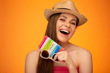 Laughing woman in Mexican hat wearing holding passport for new summer journey. isolated face close up portrait with bare shoulders on orange yellow background.
