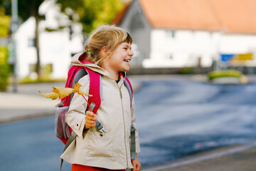 Cute little toddler girl on her first day going to playschool. Healthy happy child walking to nursery school. Kid with backpack going to day care on the city street, outdoors