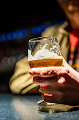 man holds a glass of beer in his hand at the bar or pub
