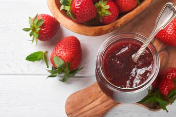 Strawberry jam. Strawberry jam in glass jar with fresh berries plate on white wooden table background, closeup. Homemade strawberry fruity jam. Top view with copy space.