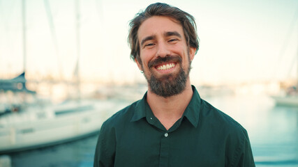 Close-up portrait of a smiling man with a beard on the embankment, on a yacht background. Frontal...