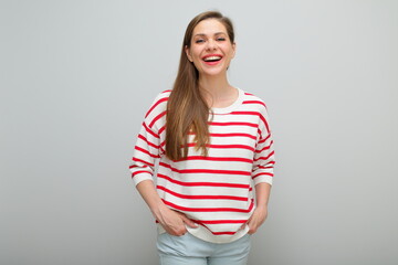 Smiling woman standing with hands in pockets, isolated female studio portrait, girl in white sweater with red stripes..