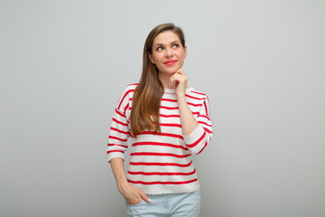 Smiling thinking woman touching her face and looking up,  isolated female studio portrait, girl in white sweater with red stripes.